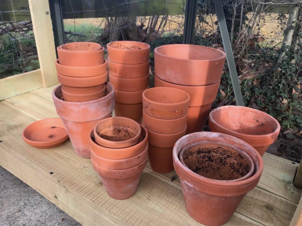 A stack of terracotta pots in garden ninjas greenhouse