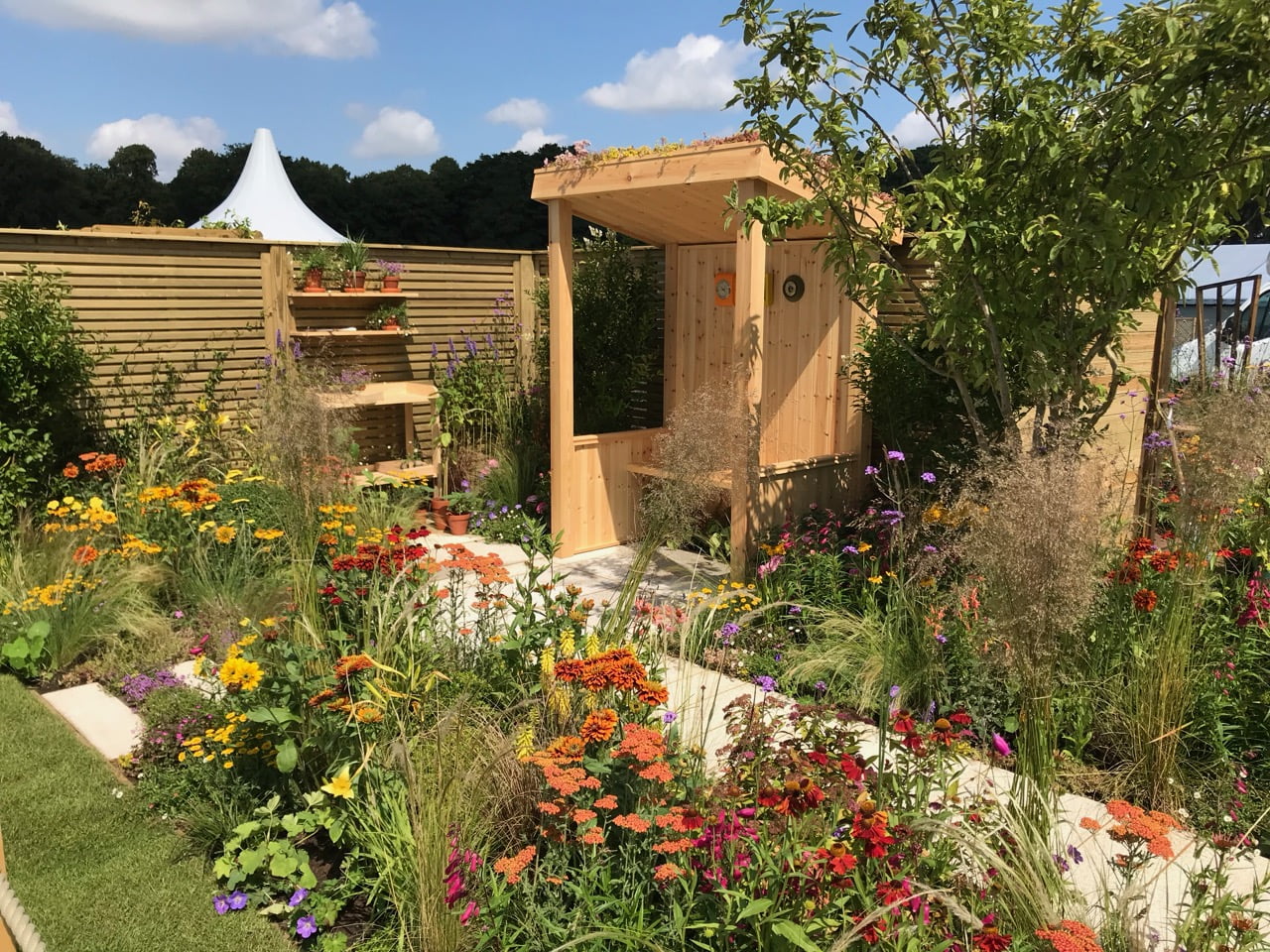 A wooden arbour with red hot herbaceous borders