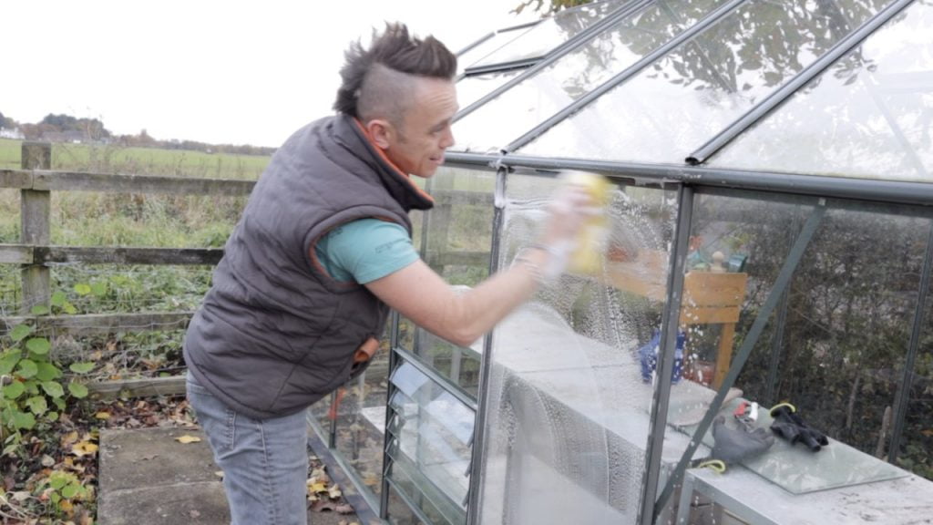 Garden Ninja washing the outside of a greenhouse